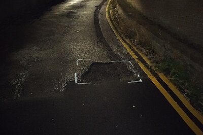 An unfilled pothole directly at the edge of a refreshly resurfaced section of road in The Undercliff, Sandgate