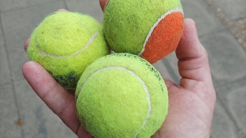 Three tennis balls held in hand